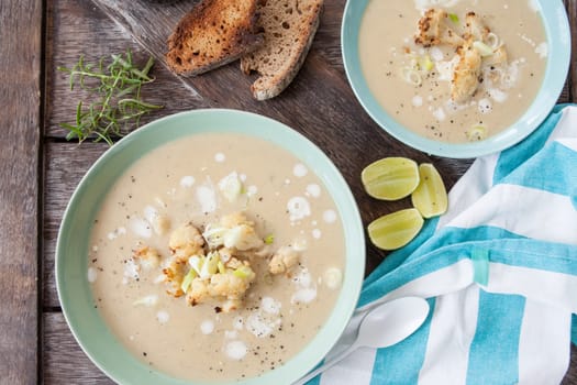 Plate of creamy soup with roasted cauliflower and spring onions