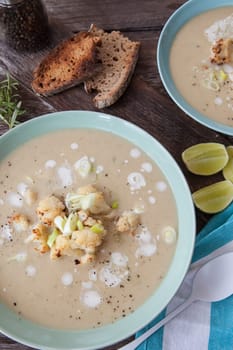 Plate of creamy soup with roasted cauliflower and spring onions