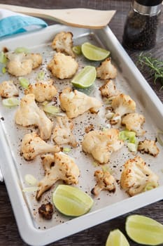 Baking sheet with roasted cauliflower and fresh lime