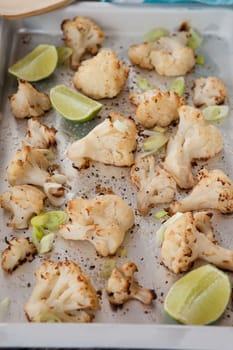 Baking sheet with roasted cauliflower and fresh lime