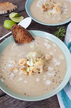 Plate of creamy soup with roasted cauliflower and spring onions