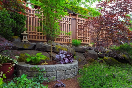 Home garden backyard landscaping with natural and stone stacked planter pots trellis lantern trees shrubs plants