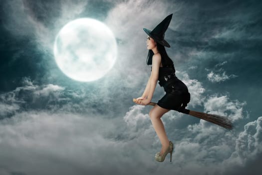 Happy asian witch woman flying above a broomstick with full moon background