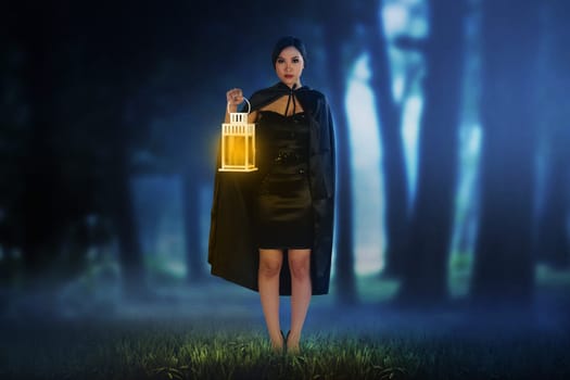 Beautiful asian witch woman holding the glowing lantern on the dark forest