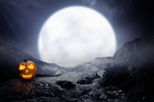 Spooky jack-o-lantern on rocky mountain with moon background