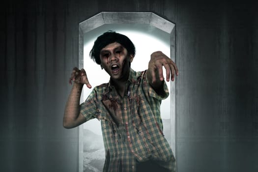 Scary zombie man coming from creepy place. Halloween concept