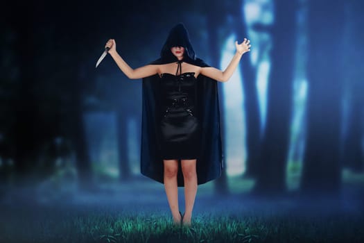 Scary asian witch woman holding knife on the dark forest