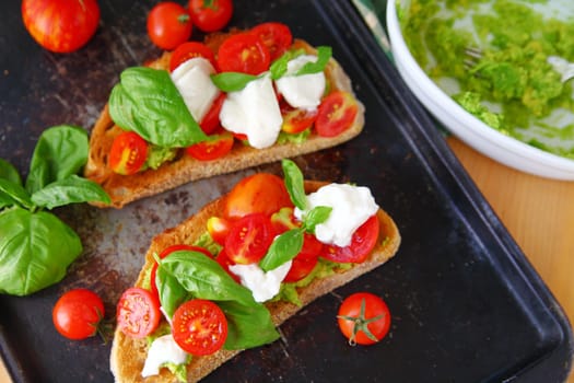 Making avocado toast with burrito cheese, cherry tomatoes and fresh basil
