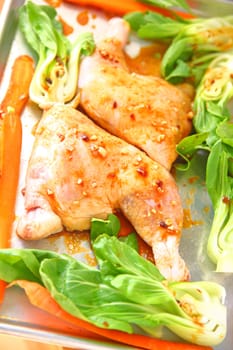 Whole chicken legs with a garlic soy marinade on a sheet pan with baby bok choy and carrots