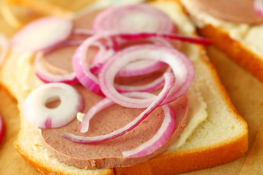 Closeup of sandwich with braunschweiger, mayonnaise and red onion slices on white bread