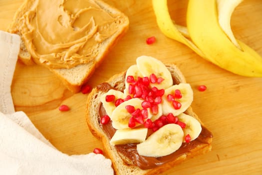 Peanut butter sandwich with chocolate hazelnut spread, bananas and pomegranate seeds
