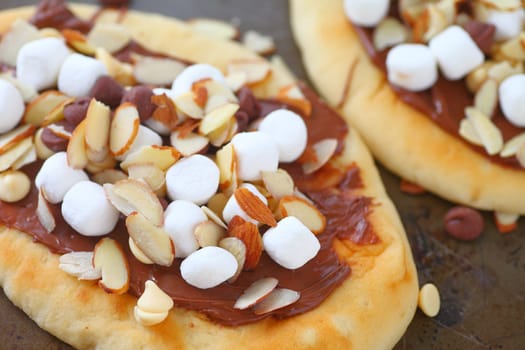 Small pizzas with chocolate spread, marshmallows, chocolate chips and almonds