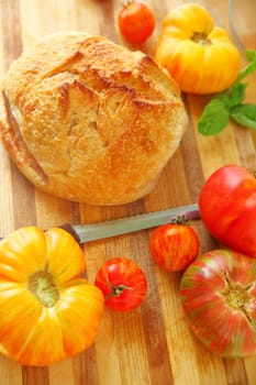 Cutting board with tomatoes and loaf of bread ready to make tomato sandwiches