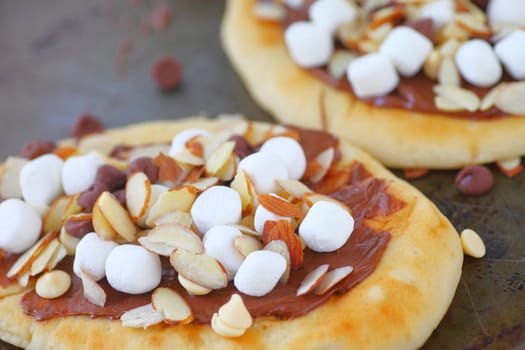 Dessert pizzas on naan bread with marshmallows, chocolate chips and almond slices