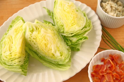 Overhead view of lettuce wedges, crumbled bacon and blue cheese