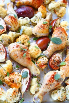 Roasted chicken legs with mini eggplants, cauliflower and fresh sage leaves