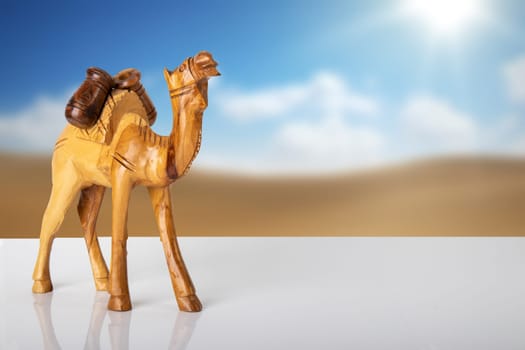 Wooden carved camel standing in table in front of blurred natural background. Place for your food and display product montage.