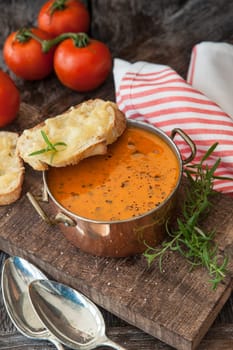 Hearty tomato soup with rosemary and slices of cheese baguette