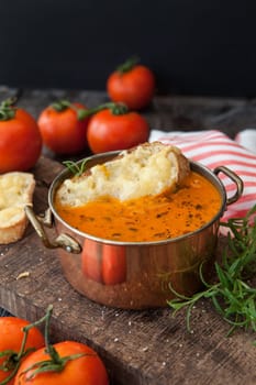 Hearty tomato soup with rosemary and slices of cheese baguette