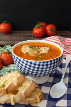 Hearty tomato soup with rosemary and slices of cheese baguette
