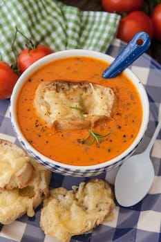 Hearty tomato soup with rosemary and slices of cheese baguette