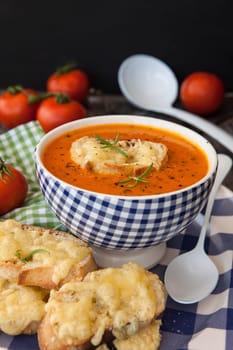 Hearty tomato soup with rosemary and slices of cheese baguette
