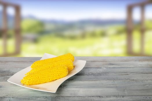 Ripe fresh corn fruits on rustic wooden table in front of natural blurred background. For your food and product display montage. Concept food.