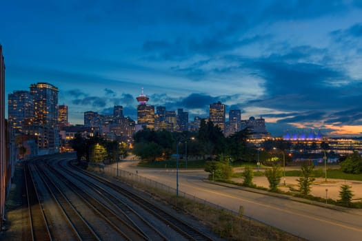 Vancouver BC British Columbia Canada downtown city skyline by railroad tracks during evening blue hour after sunset