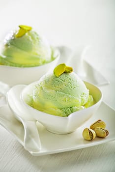 A scoop of pistachio ice cream with pistachios on white background