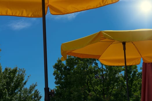 Two yellow parasols with bright sun and blue sky