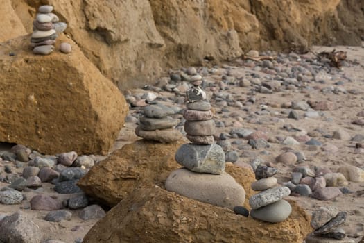 Stones stacked on top of each other on the beach in the background the cliff