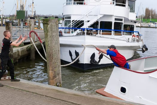 Carolinensiel, Germany - April 17, 2018: Mooring maneuver with two boatsmen of a passenger ship in the harbor of Carolinensiel. Boatmen throw themselves