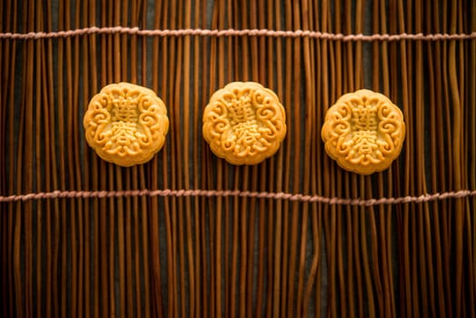 Traditional pastry mooncakes is eaten during the Mid-Autumn Festival. Flatlay on table, top down view low light with copy space. The Chinese character represent "lotus paste""."
