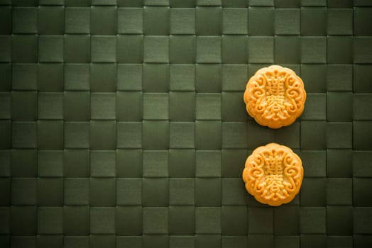 Traditional pastry moon cakes is eaten during the Mid-Autumn Festival. Flatlay table top view low light with copy space. The Chinese character represent "lotus paste""."