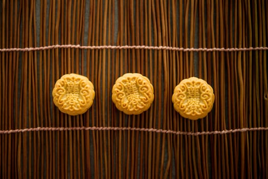 Traditional baked pastry mooncakes is eaten during the Mid-Autumn Festival. Flatlay on table, top down view low light with copy space. The Chinese character represent "lotus paste""."