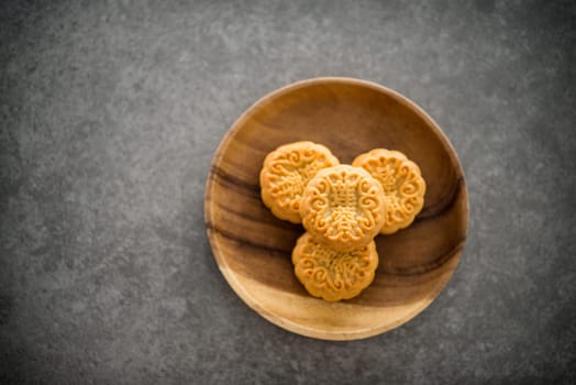 Traditional baked moon cakes is offered to friends or family during Mid-Autumn Festival. Flatlay on table top down view dark background with copy space. The Chinese character represent "lotus paste""."