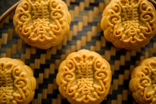 Traditional baked moon cakes is offered to friends or family during Mid-Autumn Festival. Flatlay on table, top down view dark background. The Chinese character represent "lotus paste""."