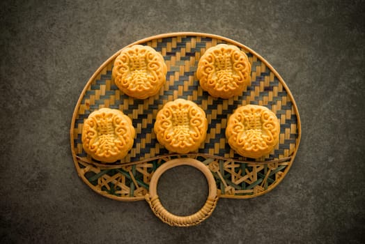 Traditional baked mooncakes is offered to friends or family during Mid-Autumn Festival. Flatlay on table, top down view dark background. The Chinese character represent "lotus paste""."