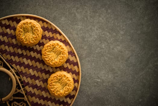 Traditional pastry moon cakes is offered to friends or family during Mid-Autumn Festival. Flatlay on table, top down view dark light with copy space. The Chinese character represent "lotus paste""."