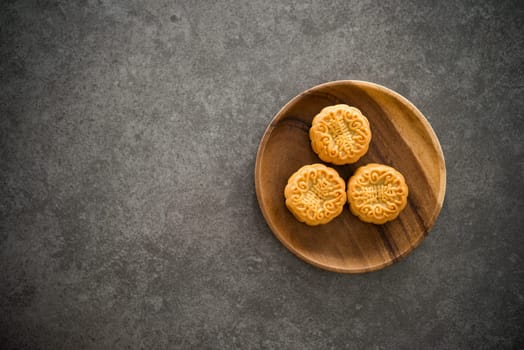 Traditional baked mooncakes is offered to friends or family during Mid-Autumn Festival. Flatlay table top view dark background with copy space. The Chinese character represent "lotus paste"" ."