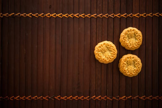 Traditional baked mooncakes is offered to friends or family during Mid-Autumn Festival. Flatlay table top view low light background with copy space. The Chinese character represent "lotus paste""."