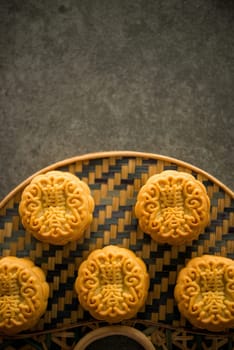 Traditional pastry mooncakes is offered to friends or family during Mid-Autumn Festival. Flatlay on table, top down view dark light with copy space. The Chinese character represent "lotus paste""."
