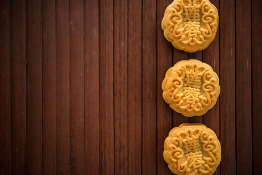 Traditional pastry mooncakes is offered to friends or family during Mid-Autumn Festival. Flatlay table top view low light with copy space. The Chinese characte represent "lotus paste""."