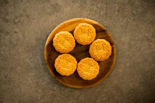 Traditional moon cakes is offered to friends or family during Mid-Autumn Festival. Flatlay table top view on dark background. The Chinese character on the mooncake represent "lotus paste"" in English."