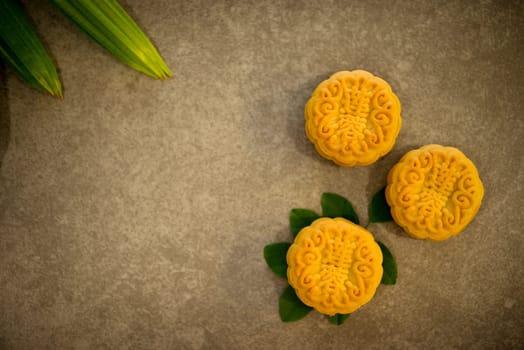 Mooncakes is traditional pastry eaten during the Mid-Autumn Festival. Flatlay on table, top down view low light with copy space. The Chinese character represent "lotus paste""."