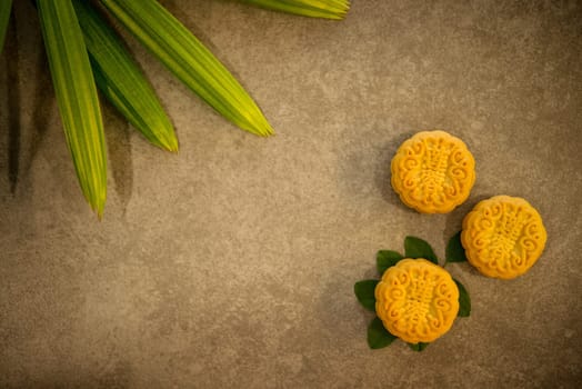 Moon cakes is traditional pastry eaten during the Mid-Autumn Festival. Flatlay on table, top down view low light with copy space. The Chinese character represent "lotus paste""."