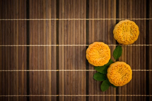 Mooncakes is traditional pastry eaten during the Mid-Autumn Festival. Flatlay on table, top down view dark light with copy space. The Chinese character represent "lotus paste""."