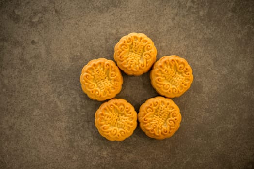 Mooncakes is offered to friends or family during Mid-Autumn Festival. Flatlay table top view on dark background. The Chinese character represent "lotus paste""."