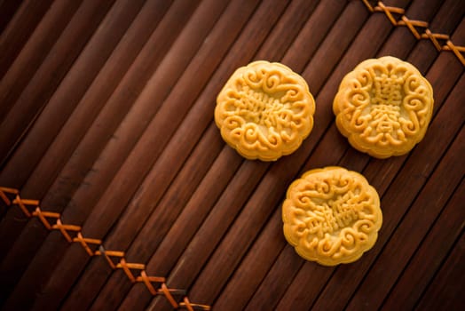 Traditional baked moon cakes is offered to friends or family during Mid-Autumn Festival. Flatlay table top view low light background with copy space. The Chinese character represent "lotus paste""."