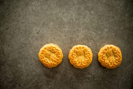 Traditional pastry moon cakes is offered to friends or family during Mid-Autumn Festival. Flatlay table top view dark light with copy space. The Chinese character represent "lotus paste""."